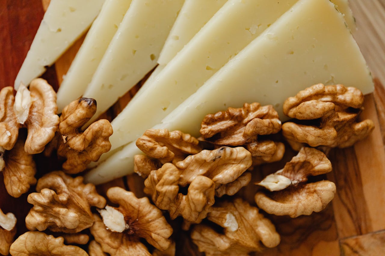 Sliced Cheese and Roasted Walnuts on Wooden Board